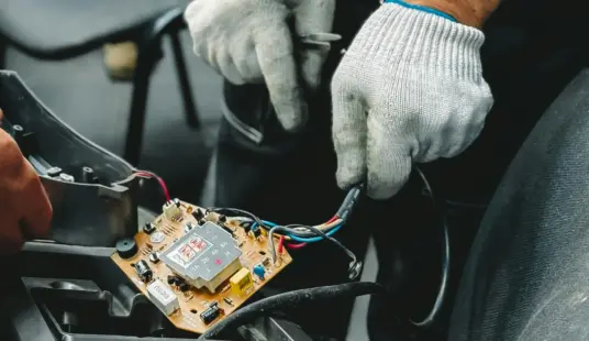 Tecnico specializzato di Italiana Ricambi che effettua un intervento di micro-riparazione su una scheda elettronica automotive in Italia.